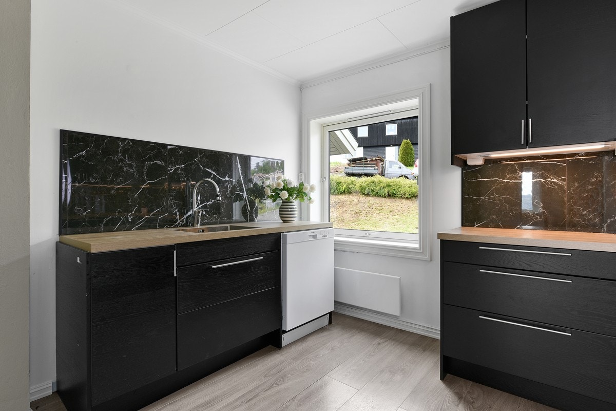 Det er mørke, slette fronter, belysning og laminert benkeplate med underlimt kum. Galleribilde