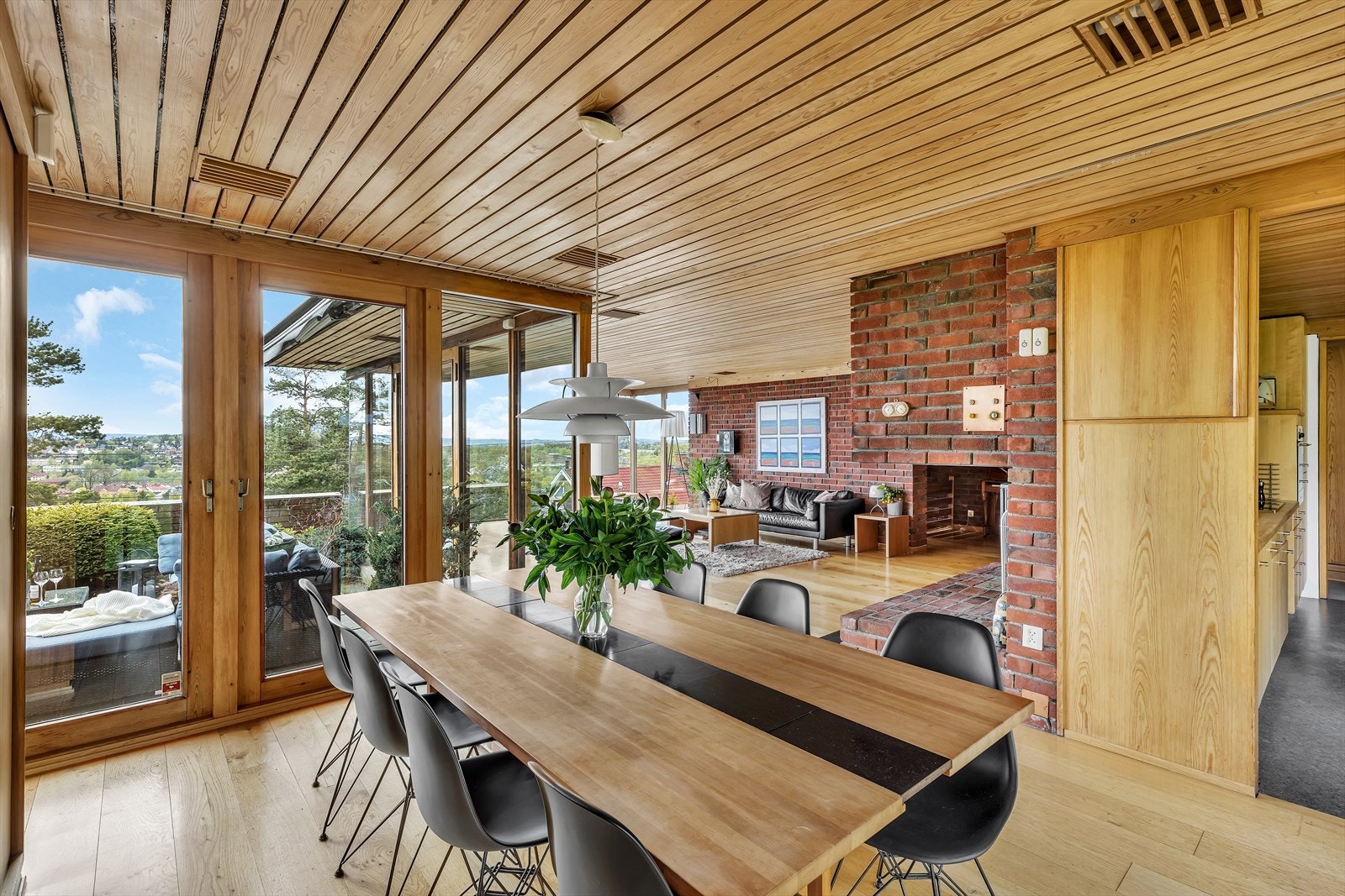 Spisestuen har vinduer fra gulv til tak mot terrassen og mot hagen Galleribilde