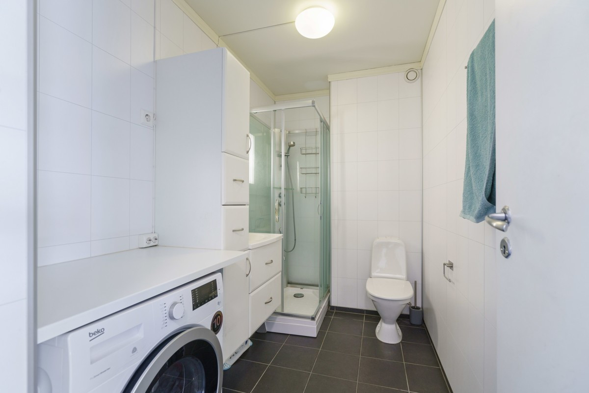 Flislagt bad er utstyrt med wc og dusjhjørne, samt opplegg for vaskemaskin
