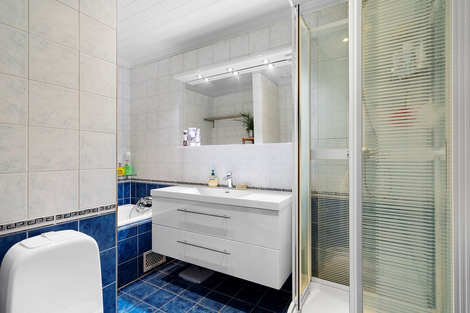 Bad innredet med dusj, innefliset badekar, servant og toalett Galleribilde