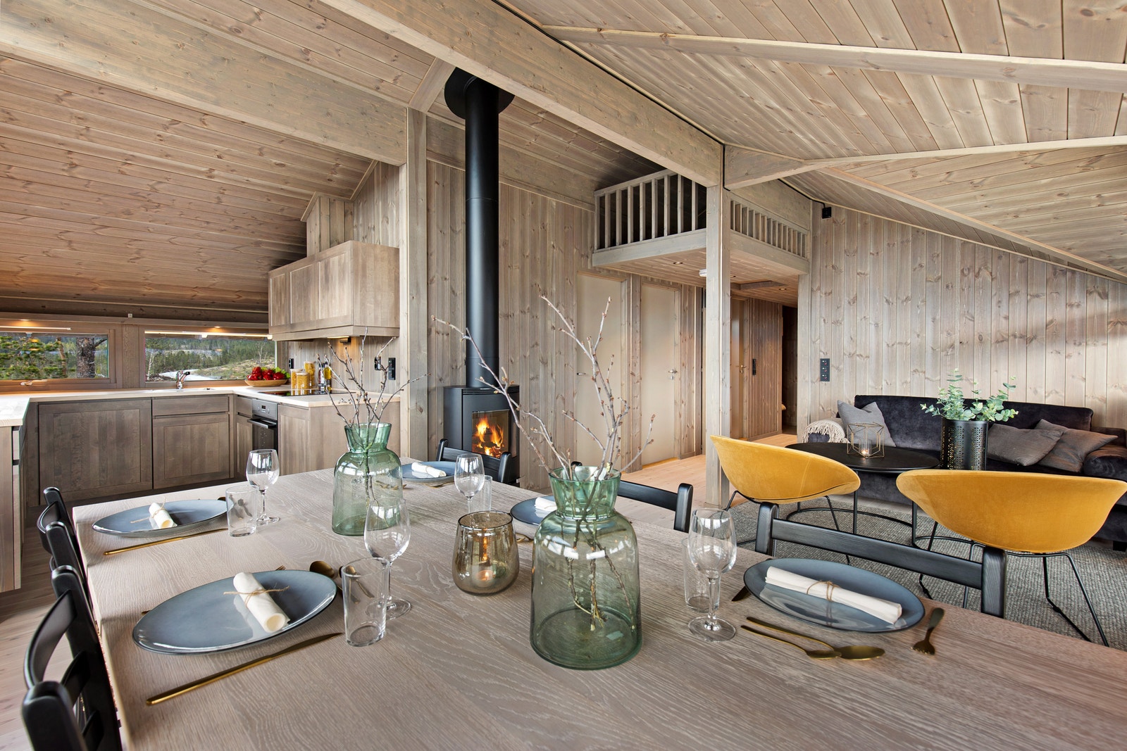 Stue og kjøkken i åpen løsning. Peisen er plassert slik at man kan nyte den fra salongen og fra spisebordet. Galleribilde