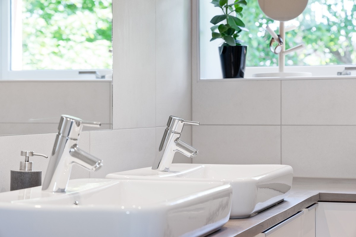 Badet er utstyrt med dusjnisje med glassdører, vegghengt toalett, dobbelservant med innredning og speil. Galleribilde