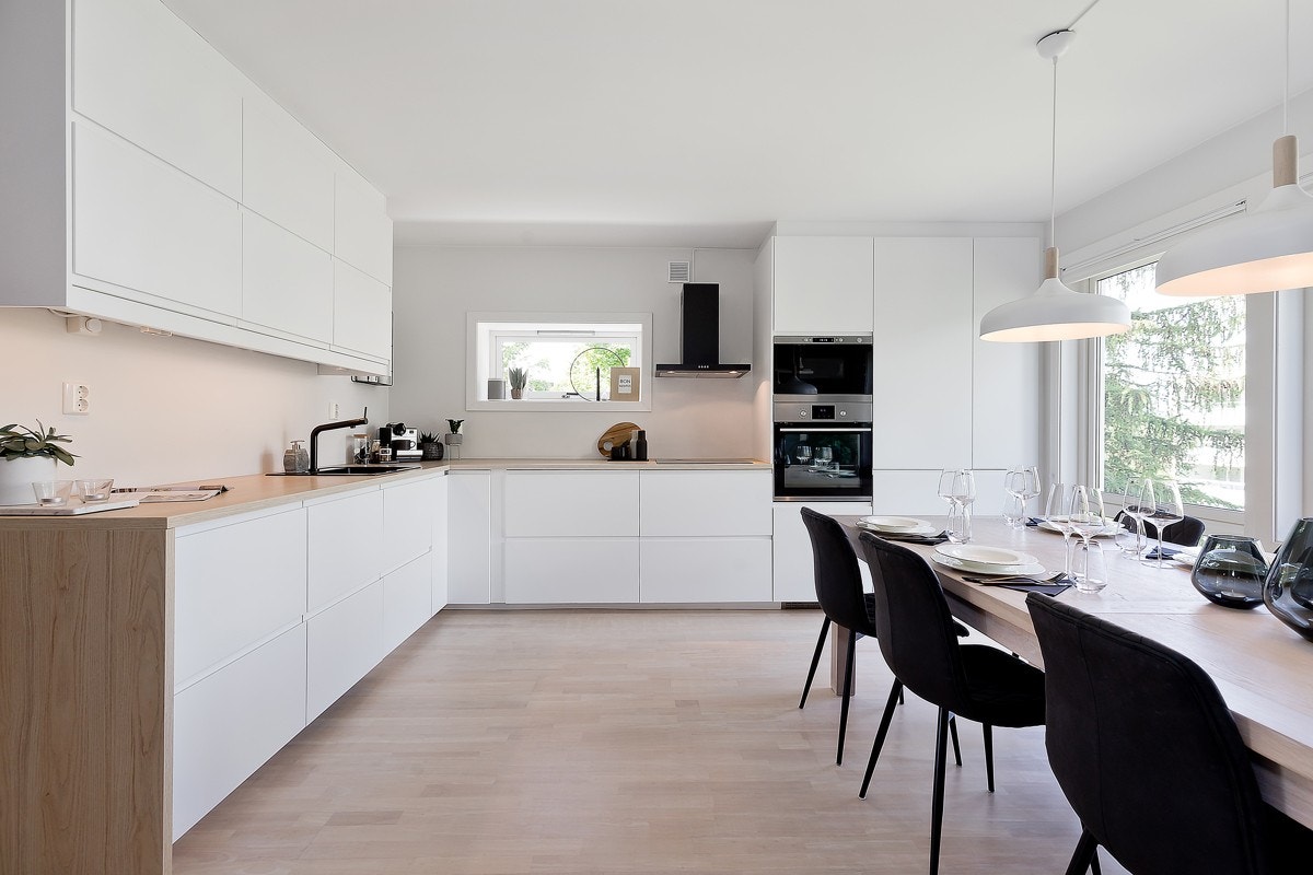 Kjøkkenet har hvite, glatte fronter, laminat benkeplate, lys under overskap og integrerte hvitevarer. Galleribilde