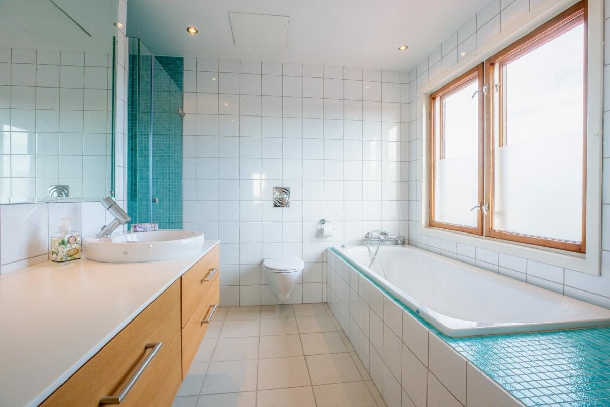 Bad med badekar, dusjnisje, wc og håndvask m/benk med oppbevaringsskuffer. Galleribilde