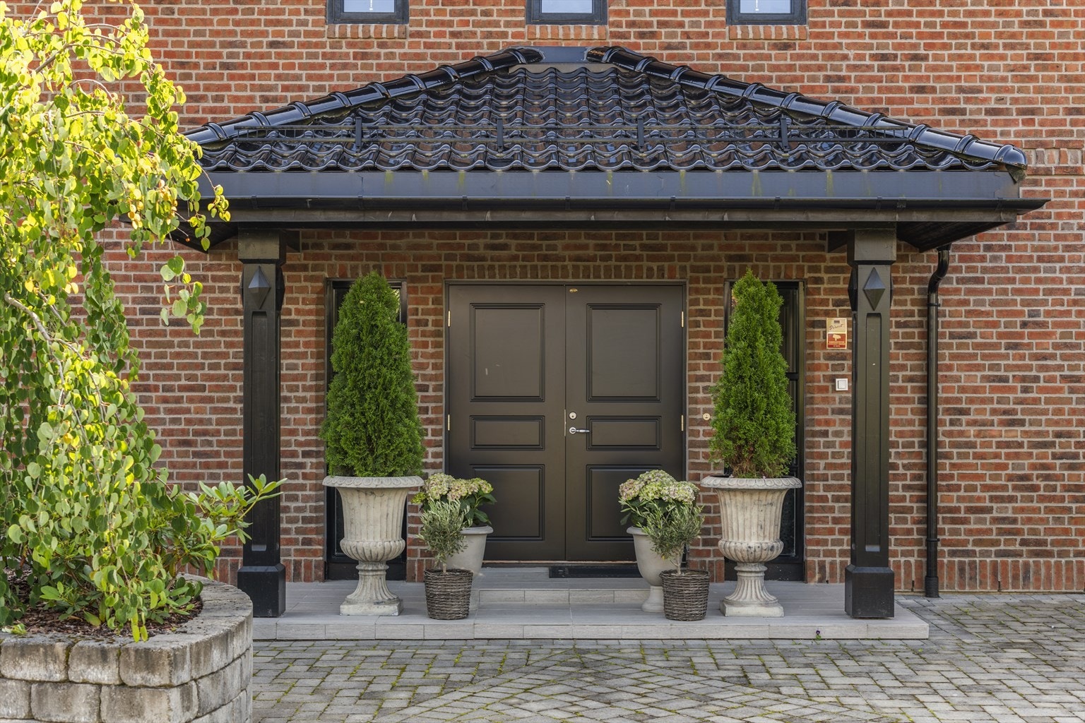 Inngangspartiet er fornemt med søyler, overbygg og høyreiste sidevinduer til tofløyet ytterdør Galleribilde