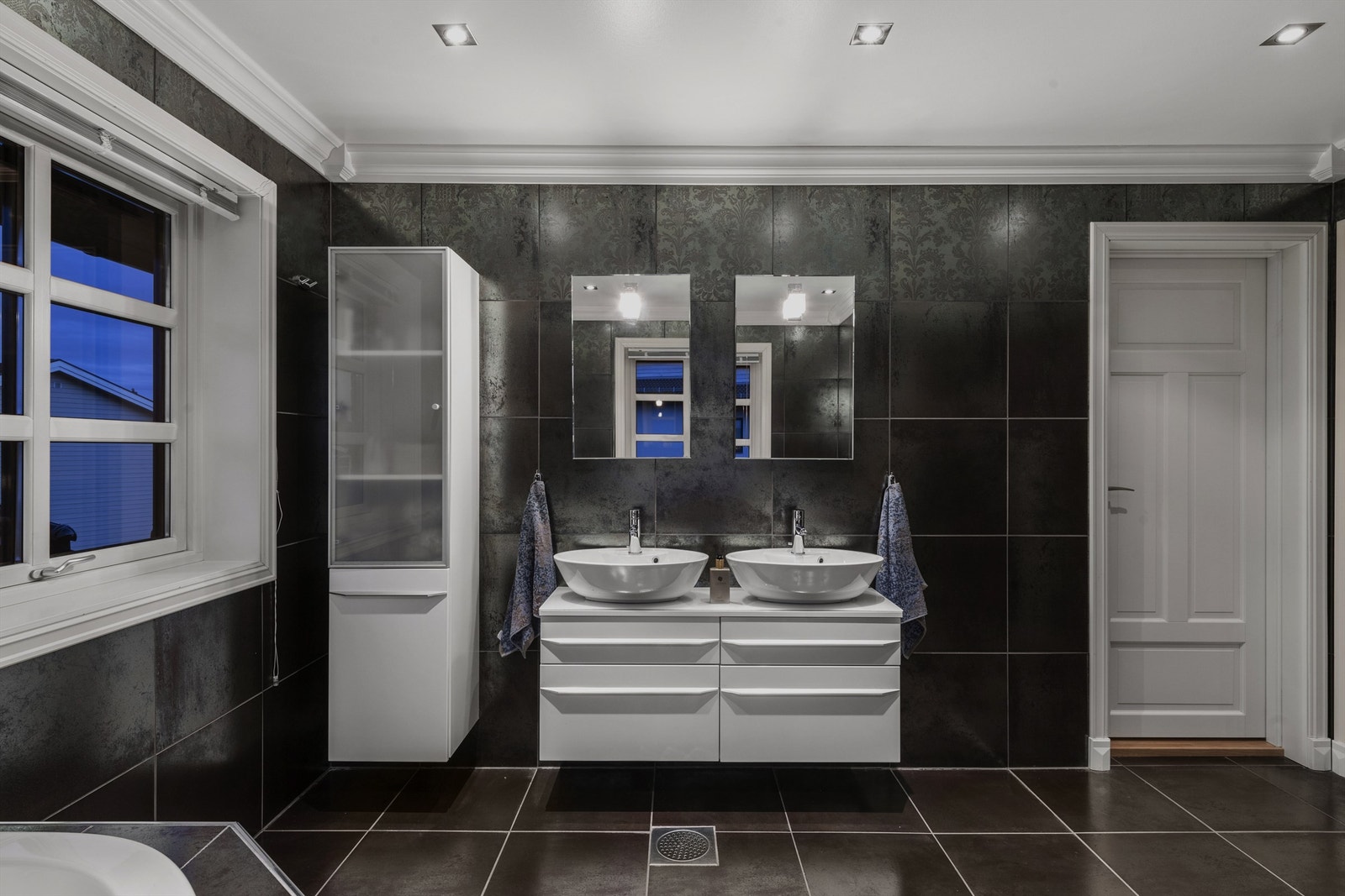 Innredningen er i hvitt; servantskap med to toppmonterte servanter og et veggskap med dels frostet front. Videre er det er det to speil med belysning Galleribilde