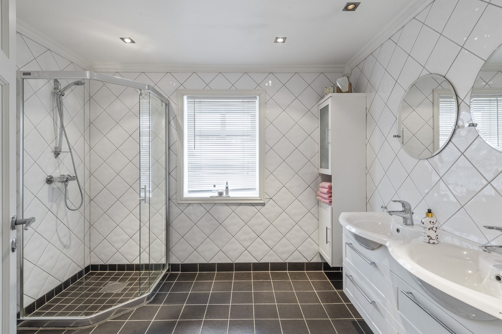 Bad 2 har skråstilte, hvite veggfliser og sorte fliser på gulv med gulvvarme Galleribilde