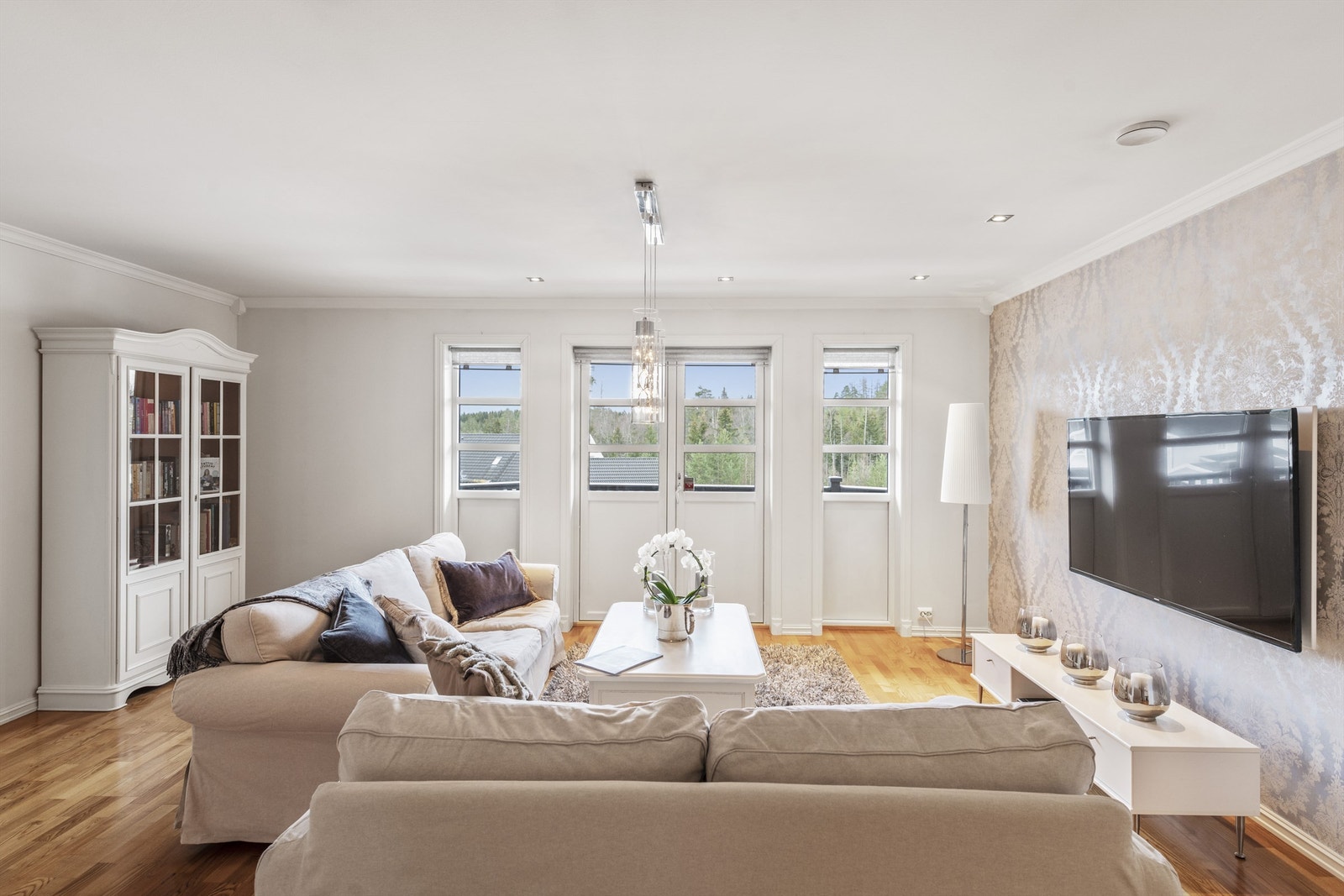 Det er enkelte downlights i tak, eikeparkett på gulv og pen, sølvmønstret tapet som harmonerer med hvitmalte flater Galleribilde