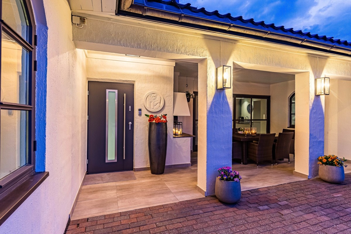 Boligen har adkomst via et overbygd inngangsparti og en sort ytterdør fra 2018 med glassfelt. Galleribilde