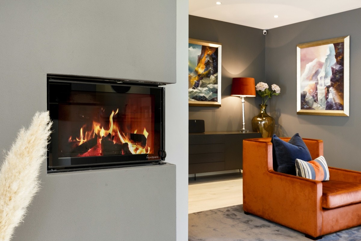 I det ene hjørnet er det satt inn en moderne peisovn fra Nordpeis med innsyn mot flammene. Galleribilde