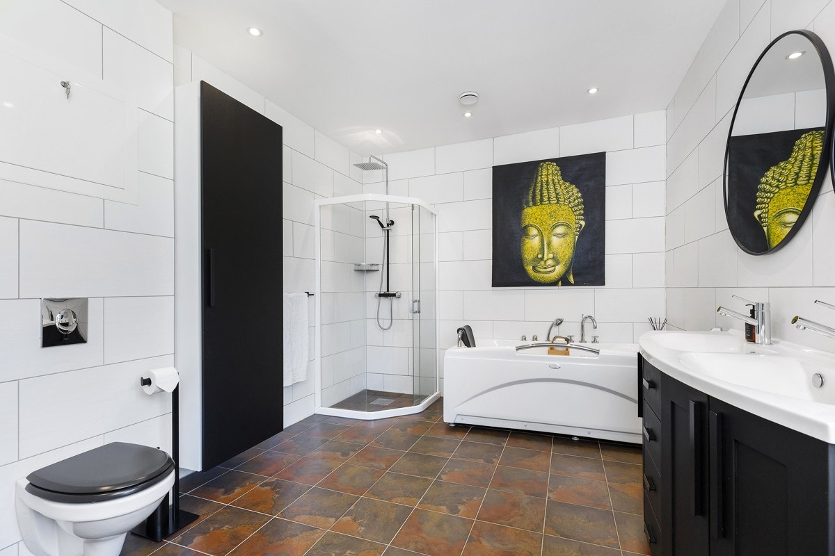 Boligen kan friste med et stort, flislagt bad med downlights i himling og varme i gulv. Galleribilde