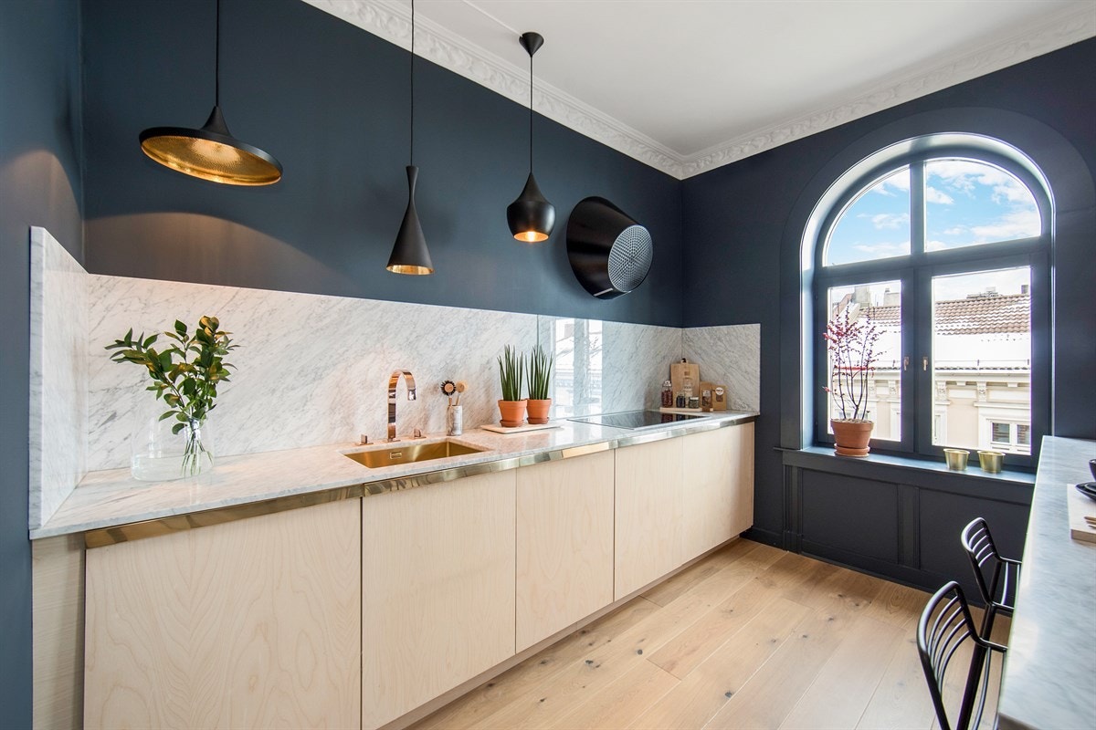 Kjøkkendelen har en stilfull, snekkertilpasset innredning med integrerte hvitevarer og lyse, glatte bjørkefronter med tilpassede messing beslag Galleribilde