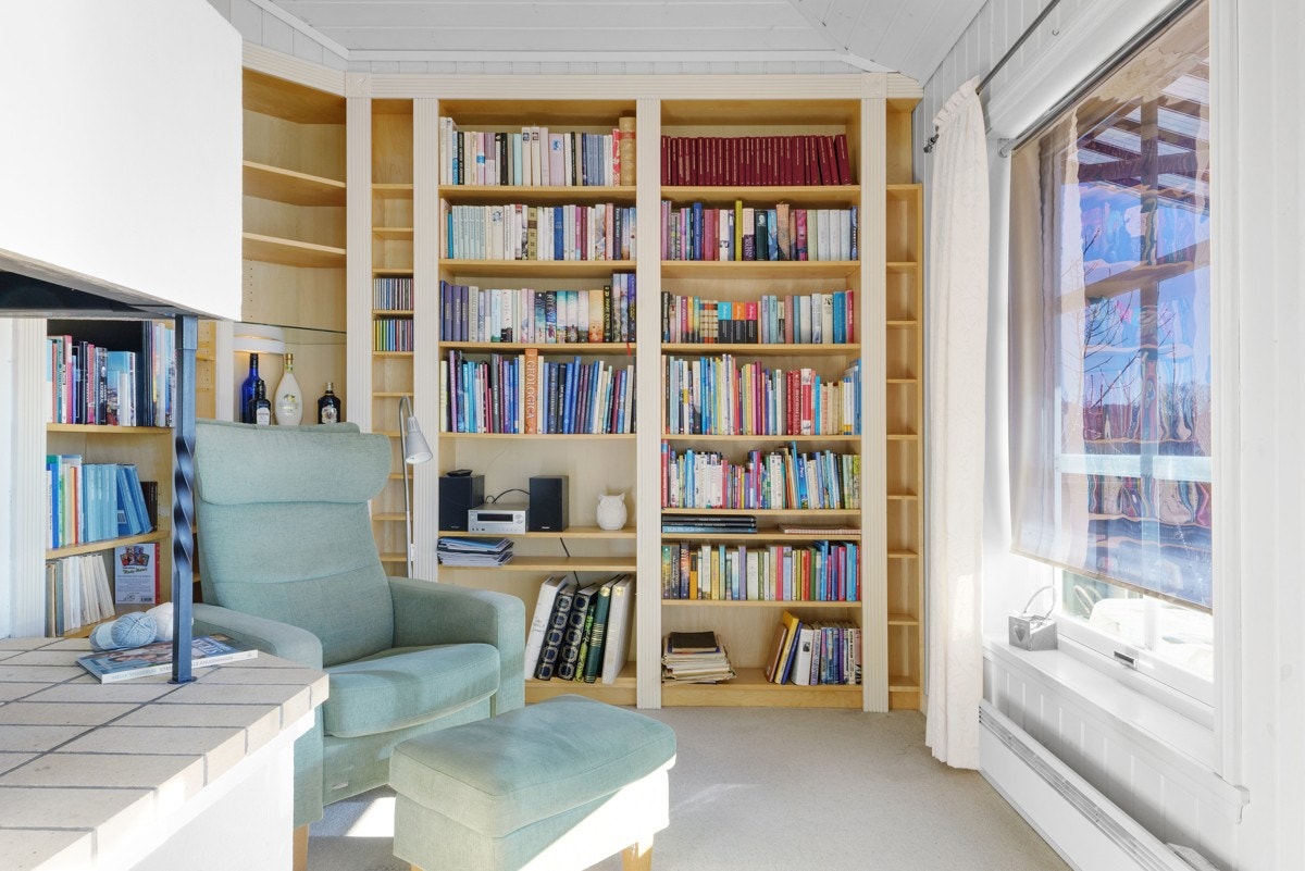 Hyggelig bibliotekskrok tilknyttet stuen med ekstra god takhøyde, plassbygget bokhylle og peis. Galleribilde