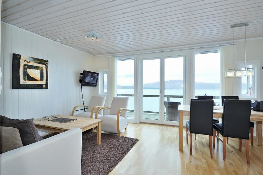 Romslig stue med parkett på gulv og rikelig med innslipp av lys fra store vindusflater
