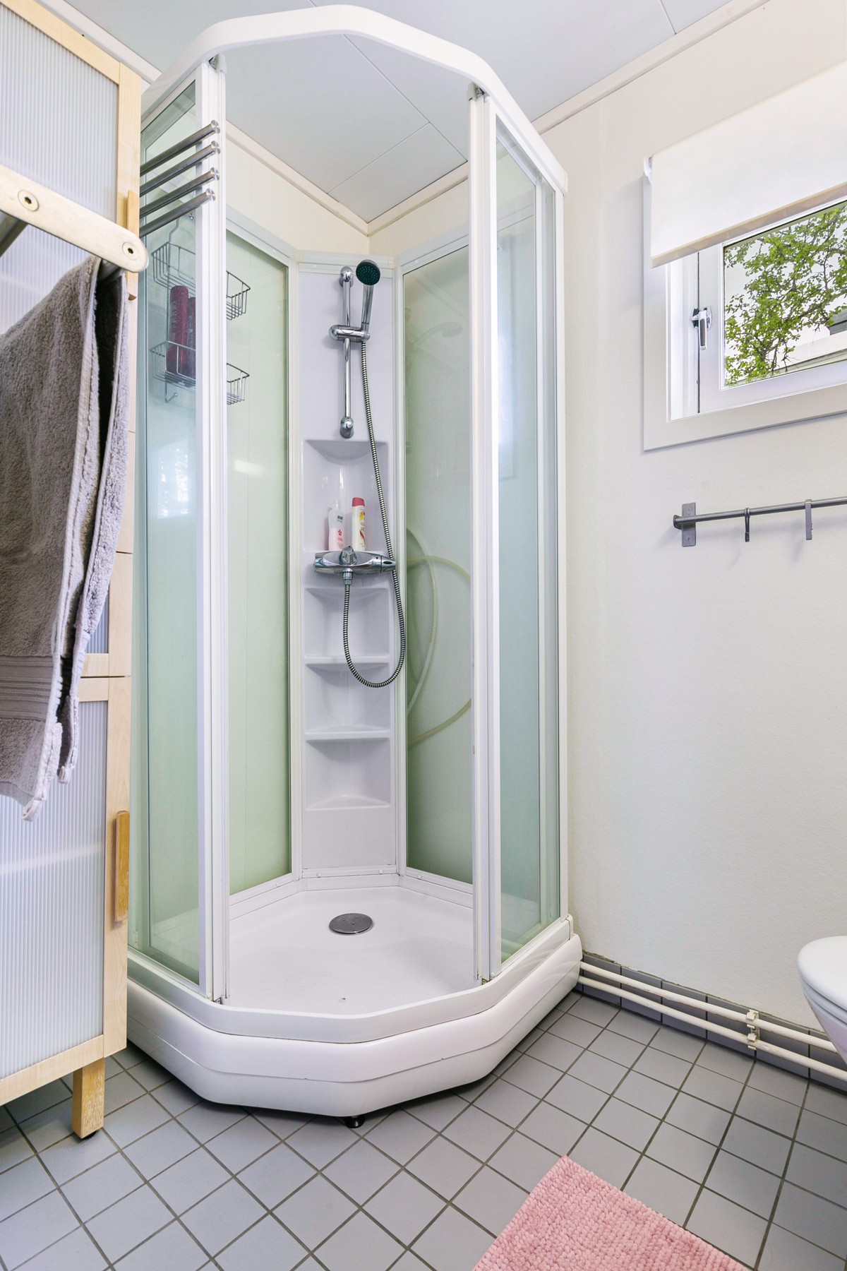 Badet er utstyrt med dusjkabinett, servantskap og toalett