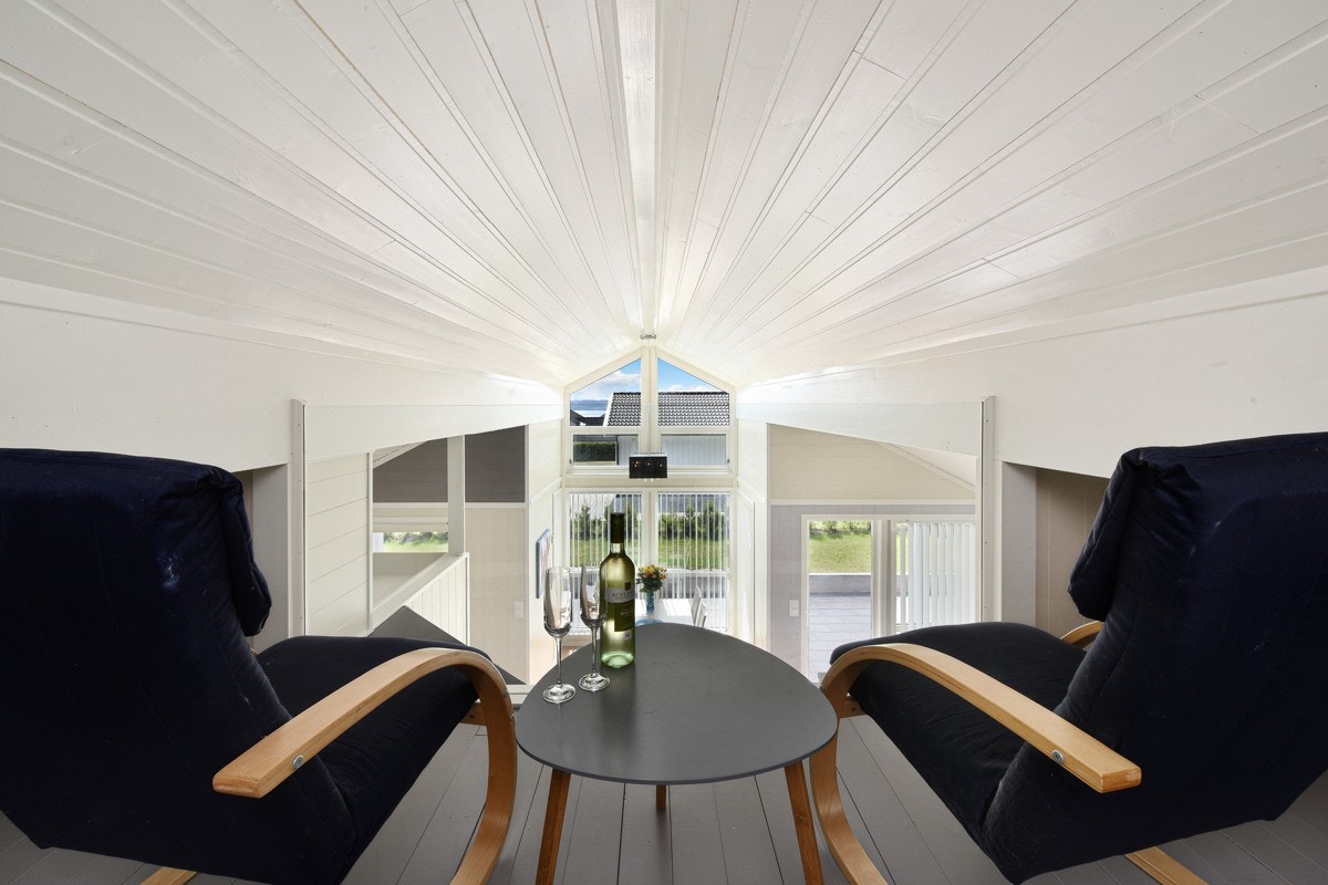 Hytta har en lun hems med malt furugulv og glassrekkverk mot stuen. Galleribilde