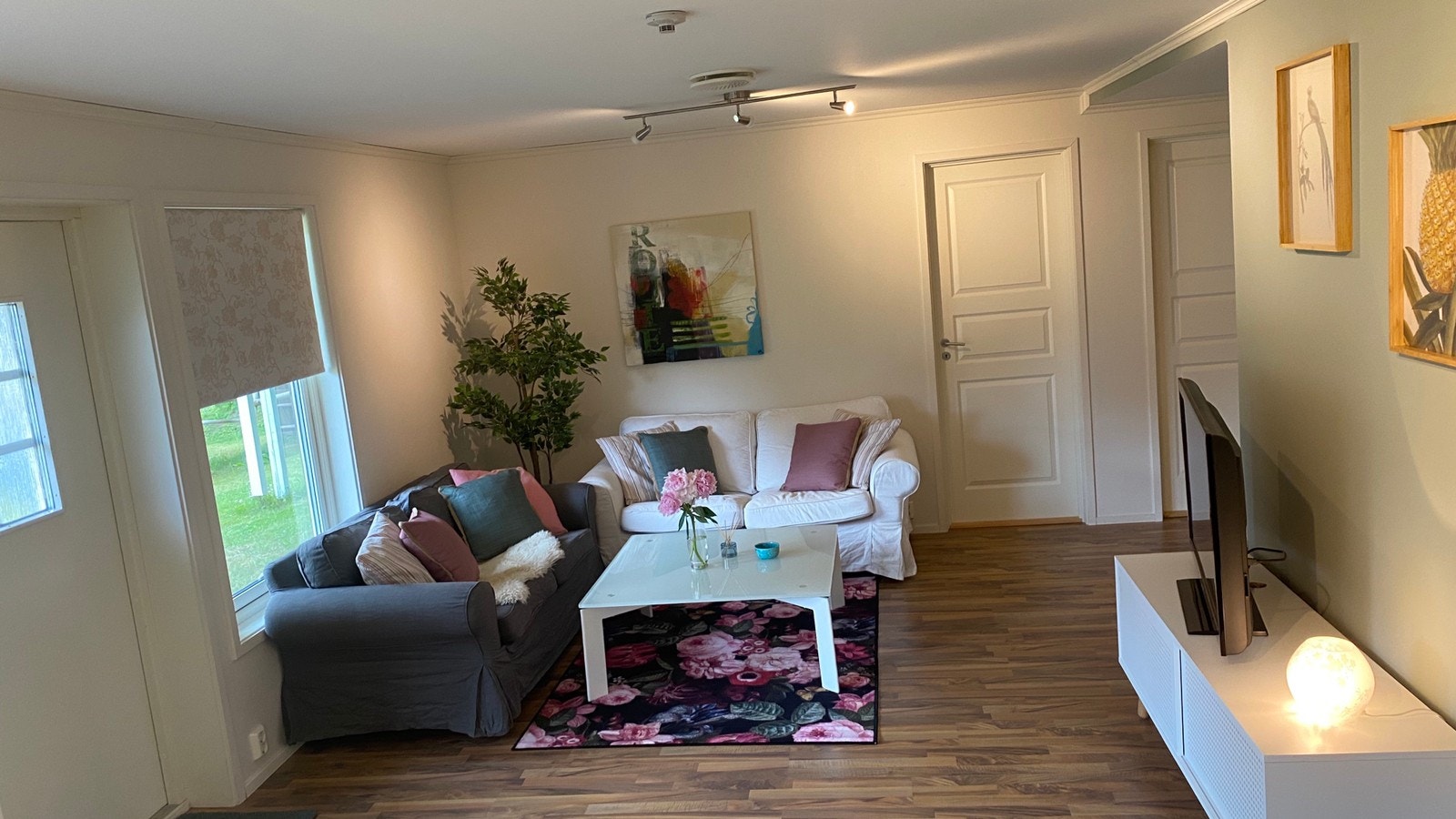 Koselig stue med 2x2 seter sofa, bord, kommode/skap og TV. Galleribilde