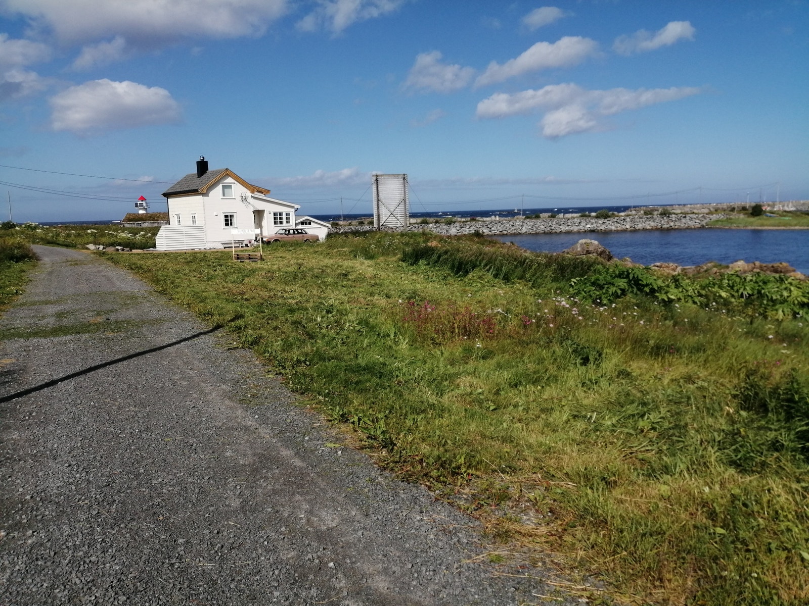 Tomten sett fra øst. Tomten ligger nærmest dette huset mot vest og går ned til sjøen. Juli 2024 Galleribilde