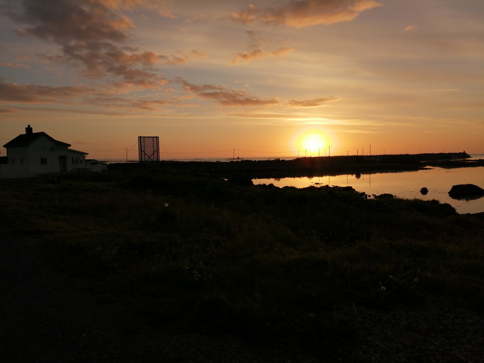 Midnattsolen som ligger over havet i vest juli 2024 Galleribilde