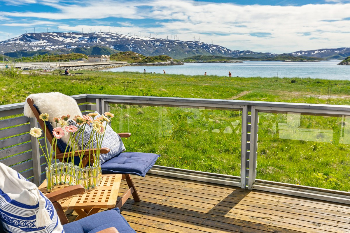 Terrasse i fin stil med terrassebord, glassflater og trekledning