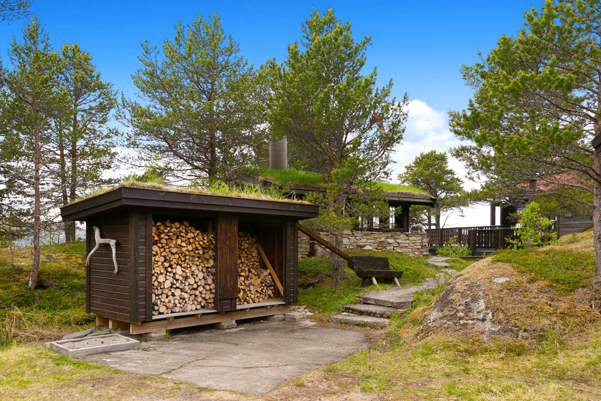 Etablert praktisk vedskjul med hellelagt gangsti opp til hytta