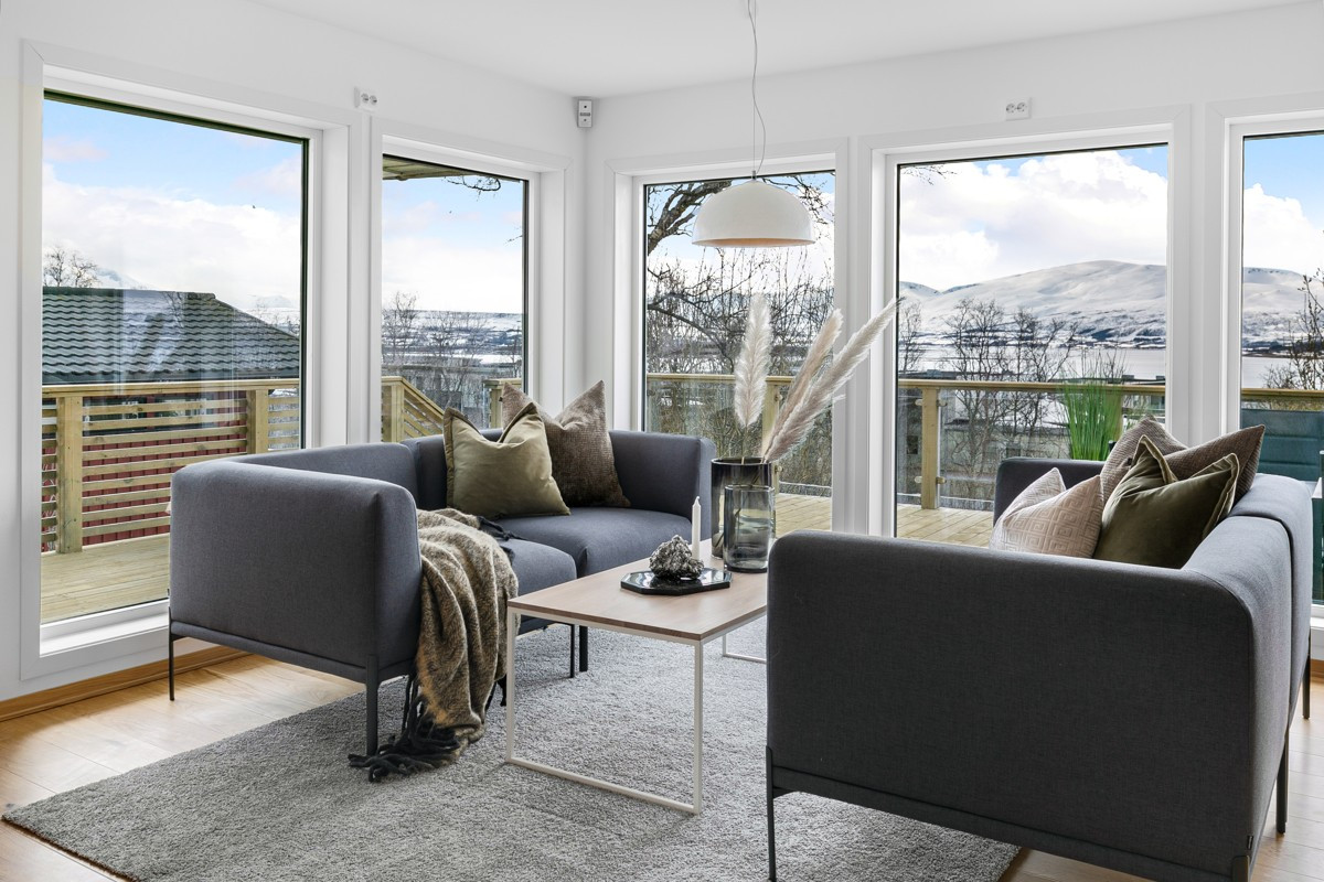 Stor stue med flere vindusflater som tar lyset og utsikten inn i rommet