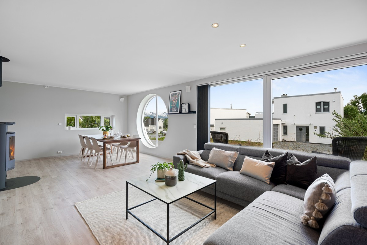 Lys og romslig stue med vindusflater fra gulv til tak og downlights i himling