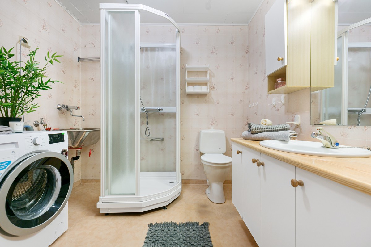 Baderom med vinylbelegg med varme, dusskabinett og opplegg for vaskemaskin
