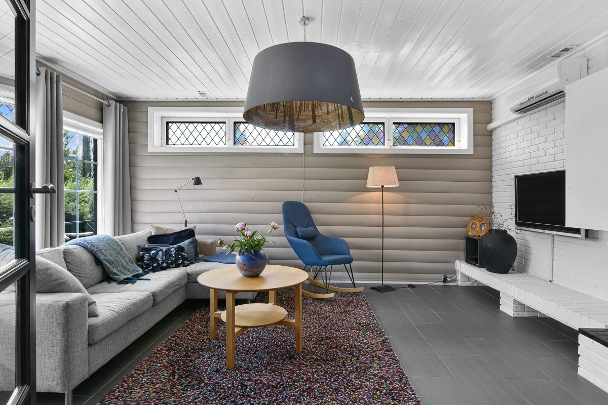 Kjellerstuen er pent innredet med beiset rundtømmerpanel på vegger og grå fliser på gulv. Galleribilde