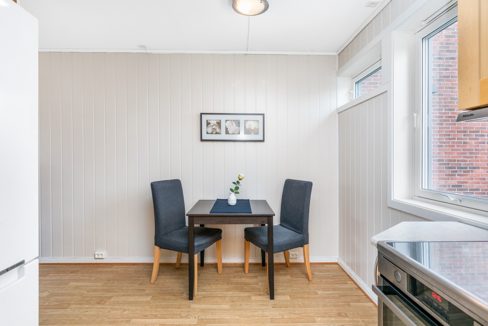 Praktisk plassering av frokostbord i overgangen til kjøkken. Galleribilde