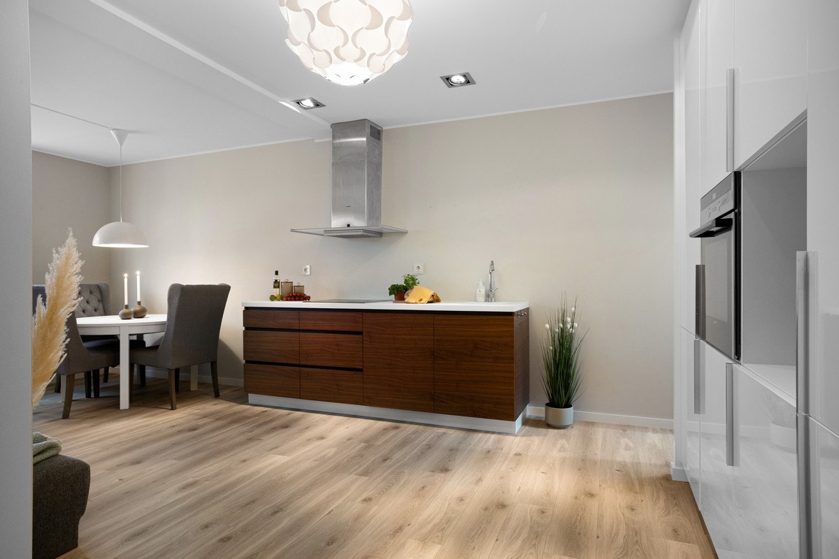 Flott kjøkken med benkeplate i kompositt med kjøkkenvask og integrert platetopp med induksjon, stekeovn, oppvaskmaskin og kjøleskap med frysedel. Galleribilde