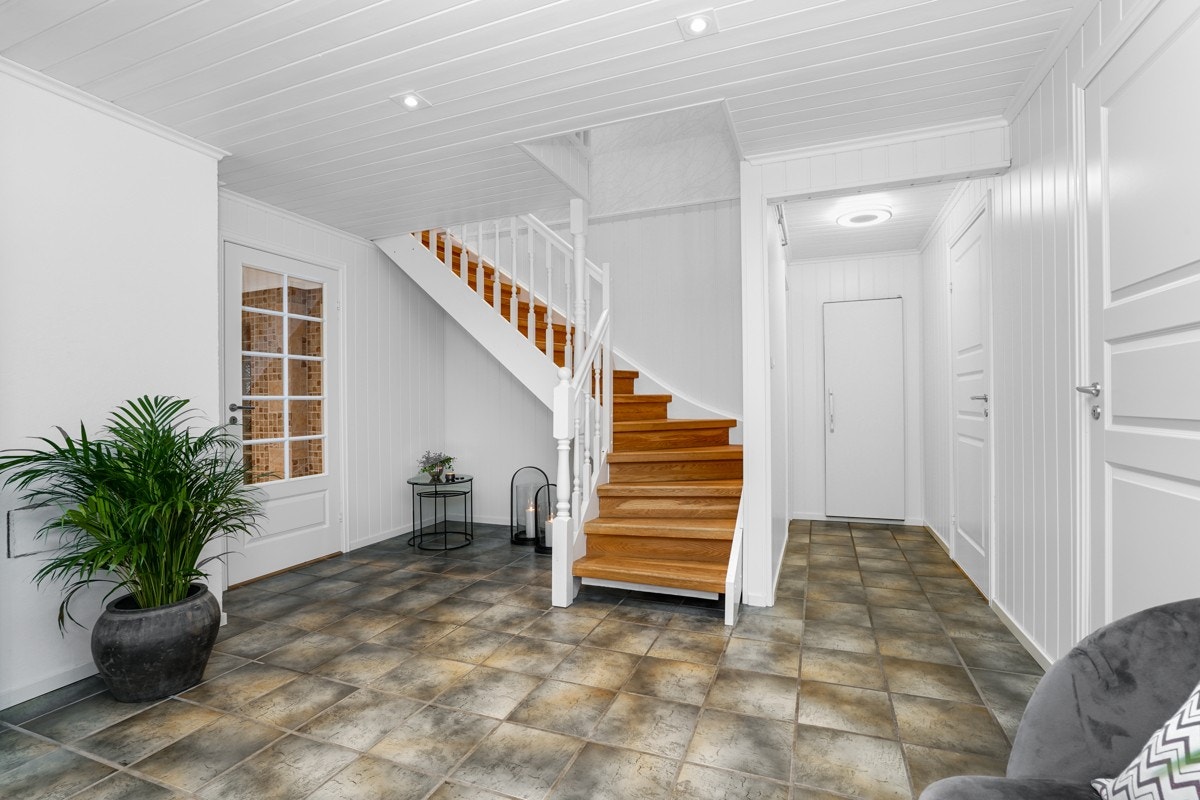 . Vel innenfor er det en luftig hall med varme i flismønstret gulv, vegger med panel og downlights i tak. Galleribilde