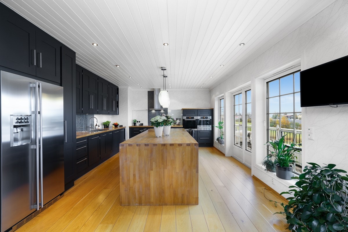 Kjøkkeninnredningen gir et flott inntrykk med profilerte, sorte fronter og heltre benkeplater i eik, som gulvet. Galleribilde