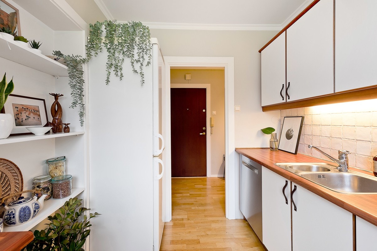 Kjøkkeninnredningen fremstår med hvite glatte fronter, benkeplater i laminat, rustfri oppvaskkum, ventilator med kullfilter og opplegg for oppvaskmaskin. Galleribilde