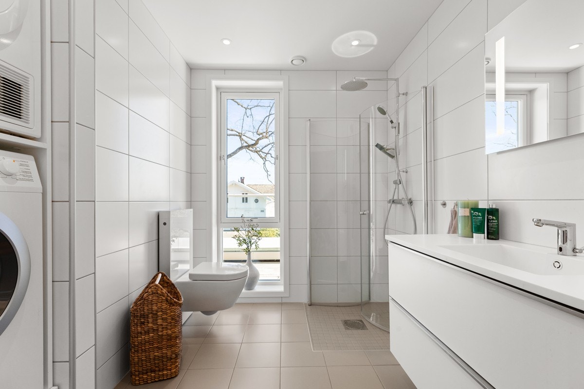 Leilighetens 2. bad er pent flislagt med varmekabler i gulv. Opplegg for vaskemaskin og tørketrommel i nisje. Galleribilde