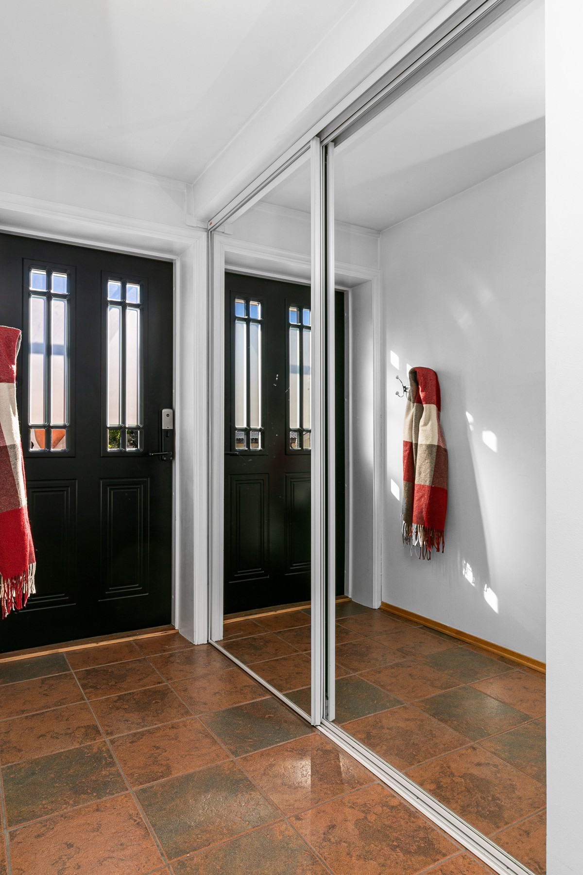 Flislagt entré med skyvedørsgarderobe