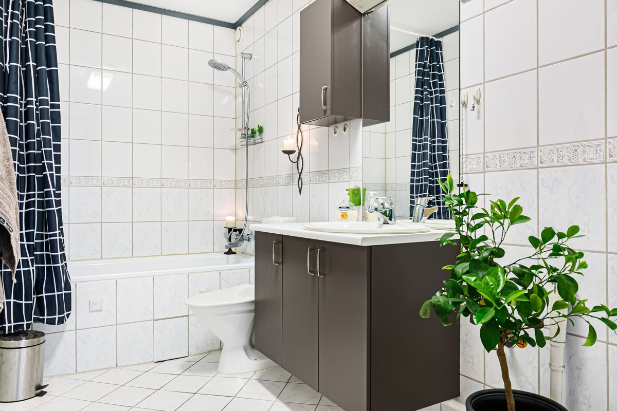 Pent flislagt bad med badekar, servantskap og opplegg for vaskemaskin