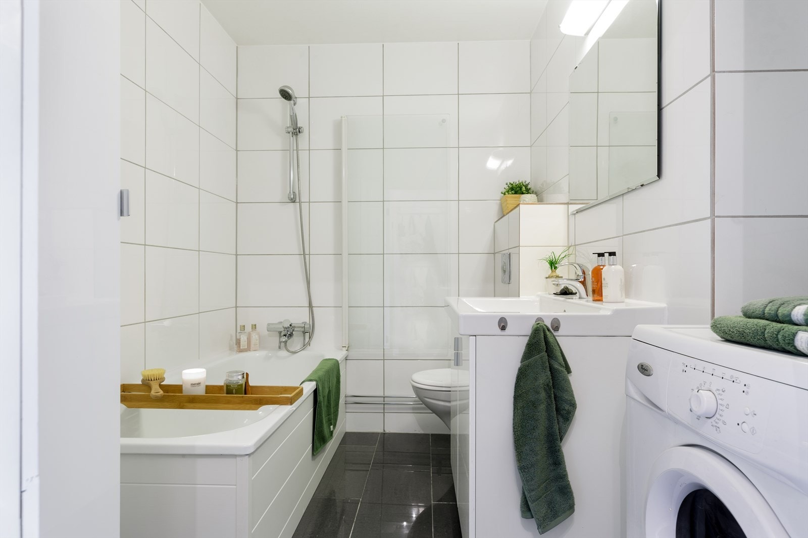 Baderommet er innredet med koksgrå fliser over varmekabler på gulv og lyse fliser på vegger. Baderommet har fått kosmetiske forbedringer. Galleribilde