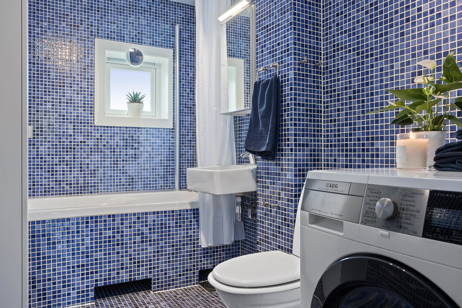 Flislagt baderom med varmekabler, badekar og vindu uten innsyn. Galleribilde