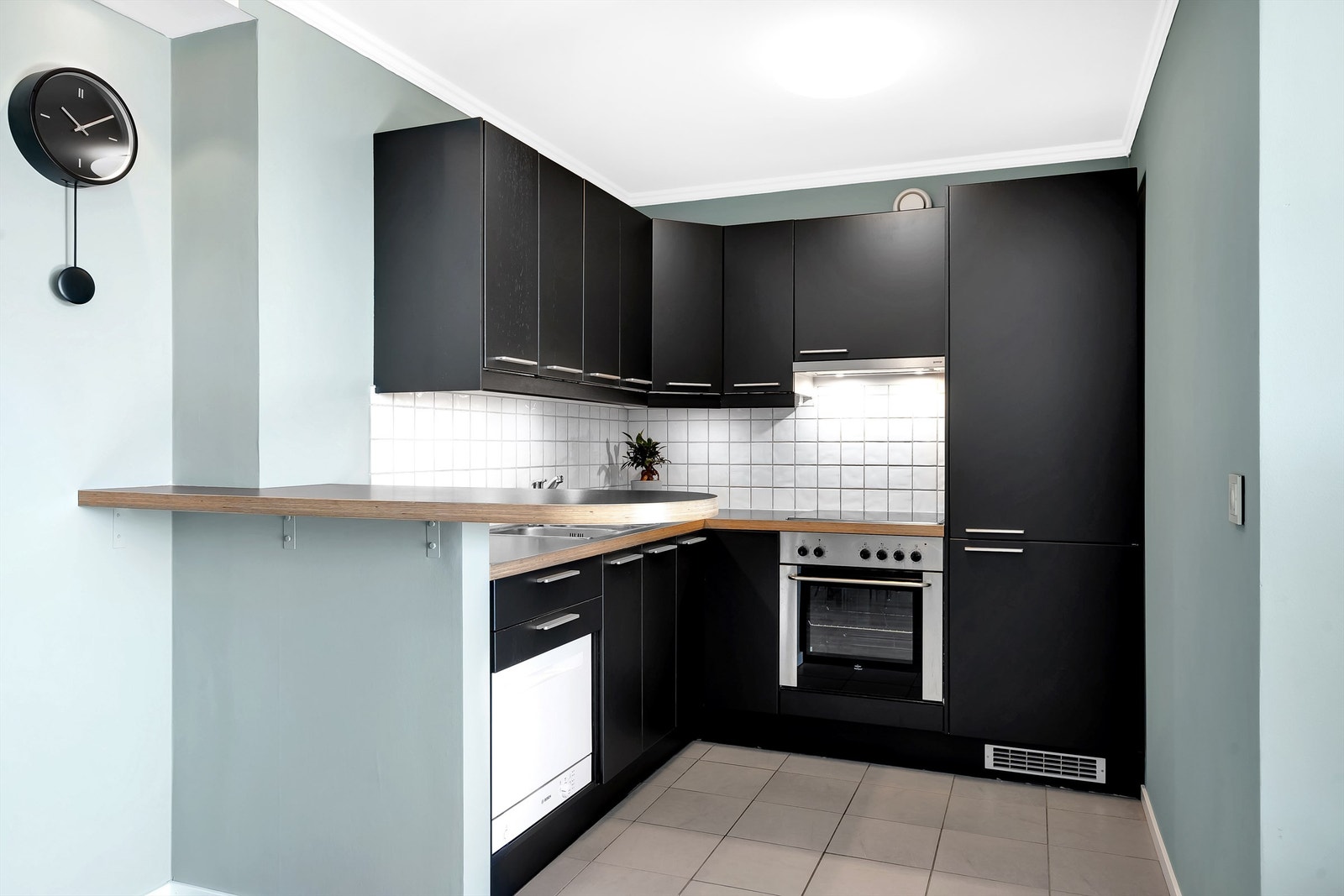 Kjøkkeninnredning med eikefinérte fronter. Benkeplate av laminert spon. Integrert i innredningen er ovn, platetopp og kjøl/frys. Galleribilde