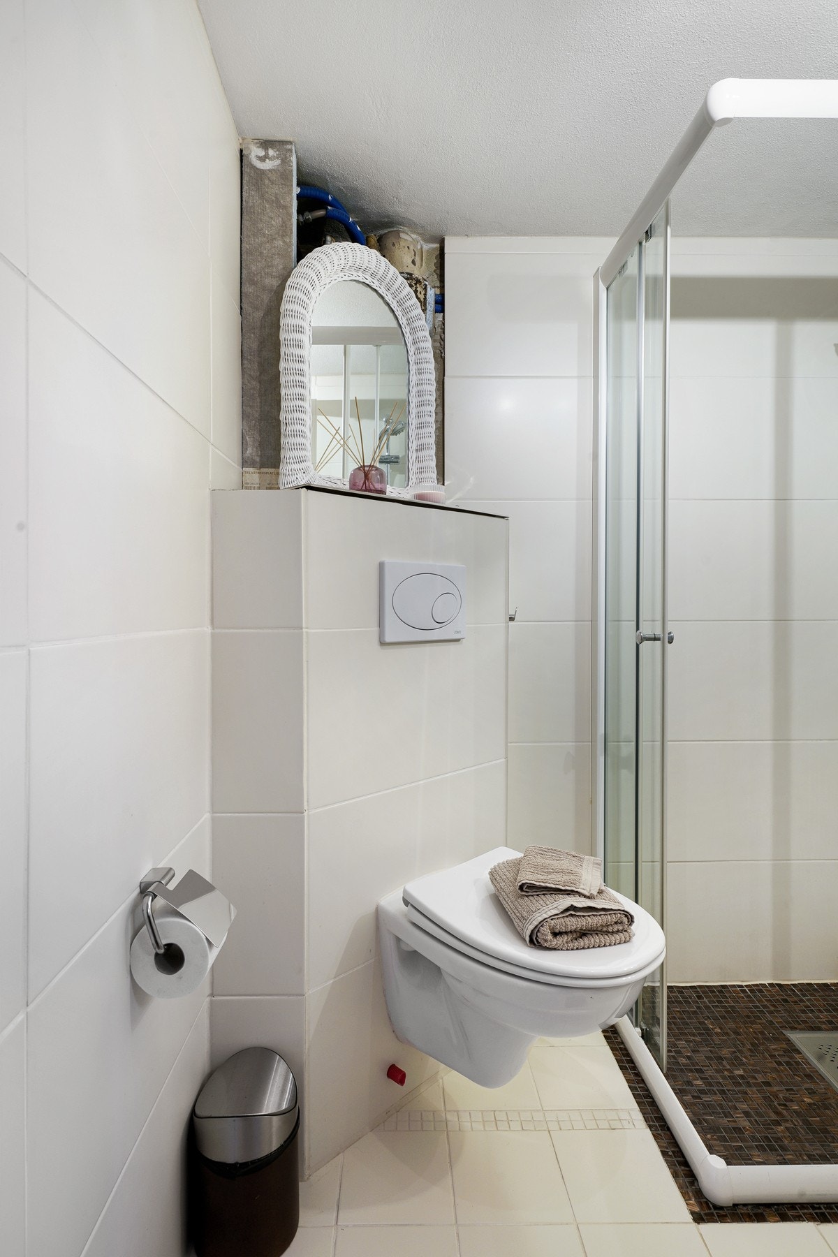 Videre har badet veggmontert toalett og dusjhjørne med dører av herdet glass. Galleribilde