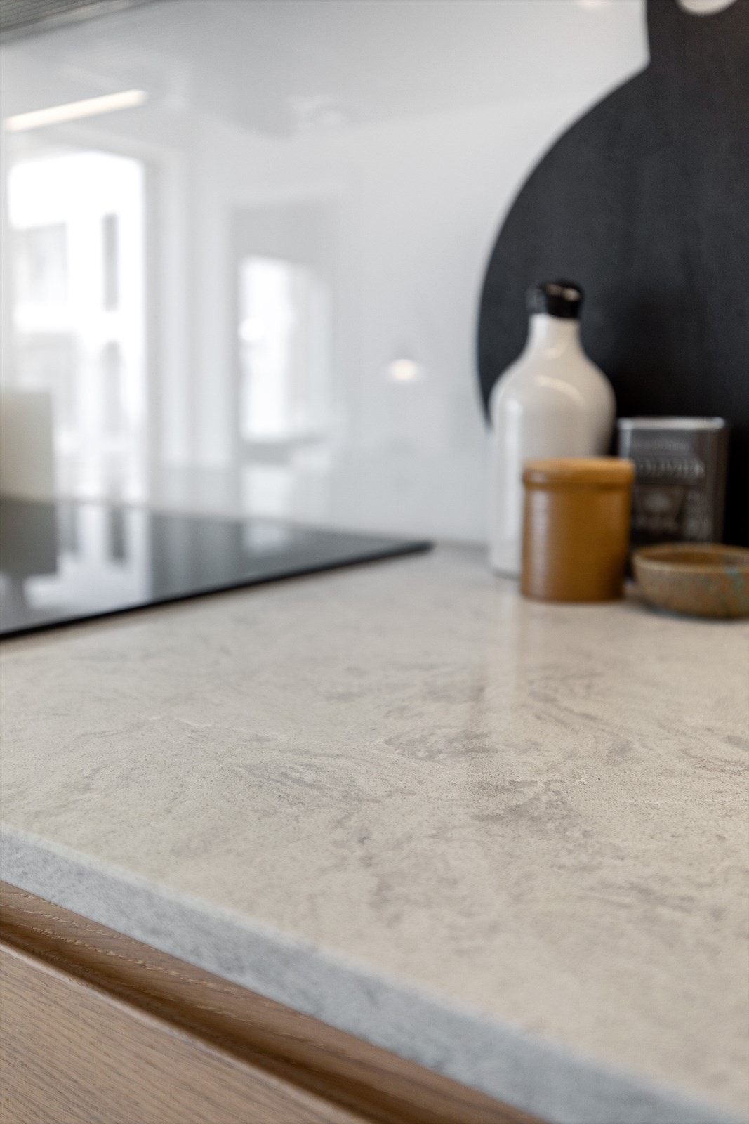 Innredning med slette fronter, glass på vegg over kjøkkenbenk og benkeplate i eksklusiv stein Galleribilde