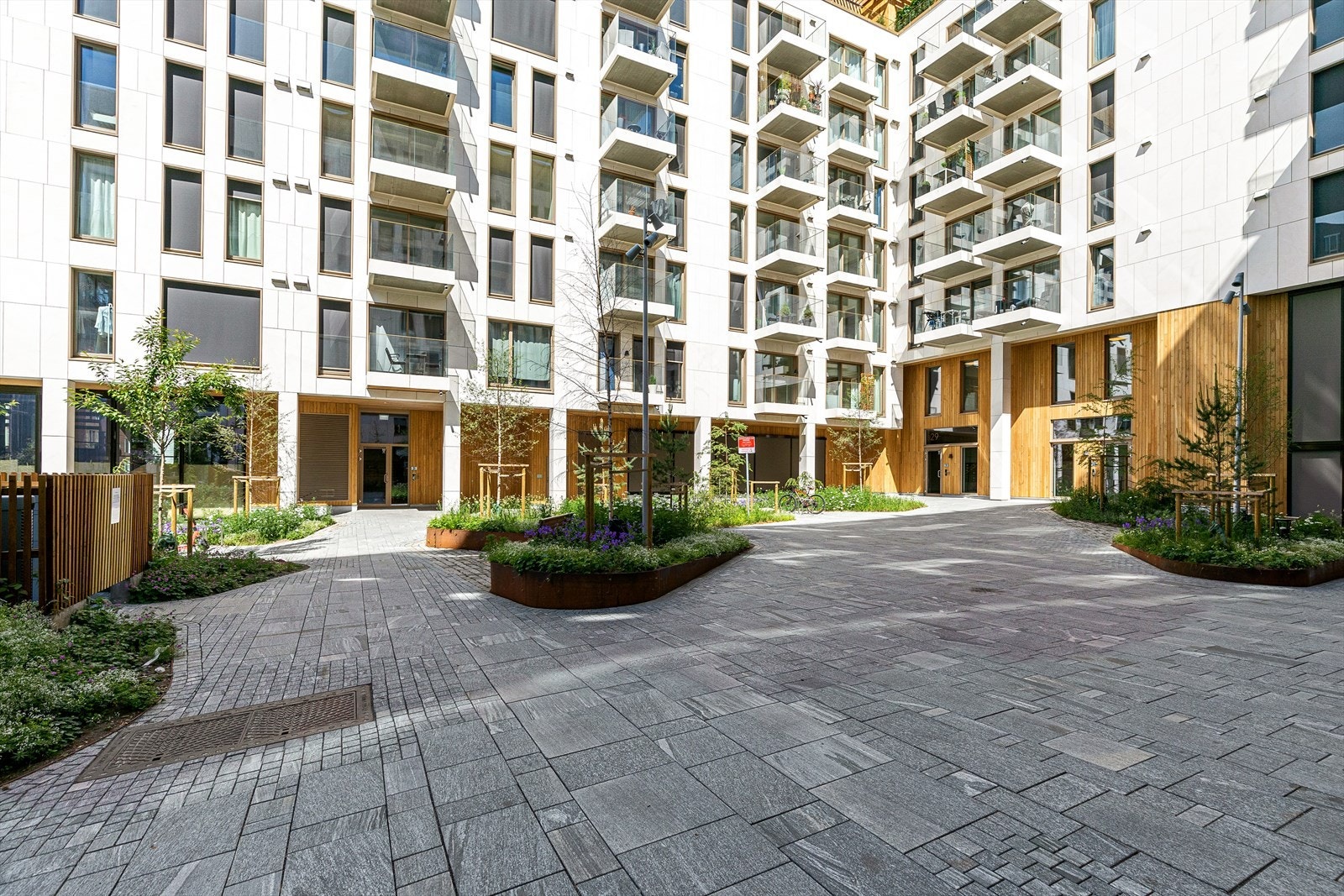 Gårdsrom opparbeidet med brostein, beplantning og sittegrupper Galleribilde