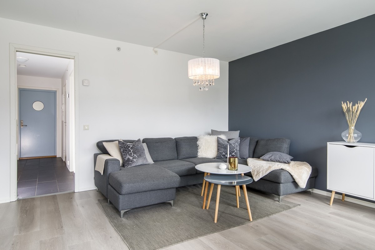 Stuen på 20 kvm har hvite vegger og en mørkere fondvegg som gir en fin dybde til rommet. Galleribilde