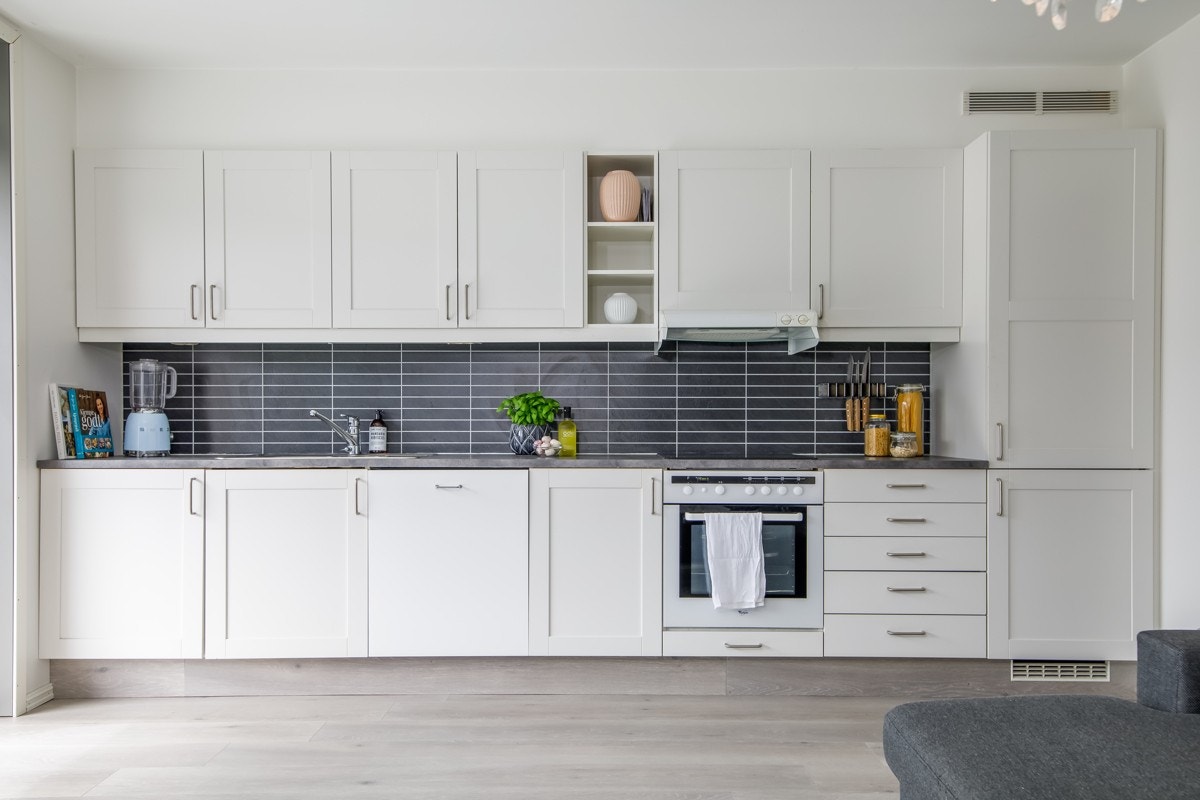 Kjøkkenet har hvit, klassisk innredning med profilerte fronter og mørk benkeplate. Galleribilde