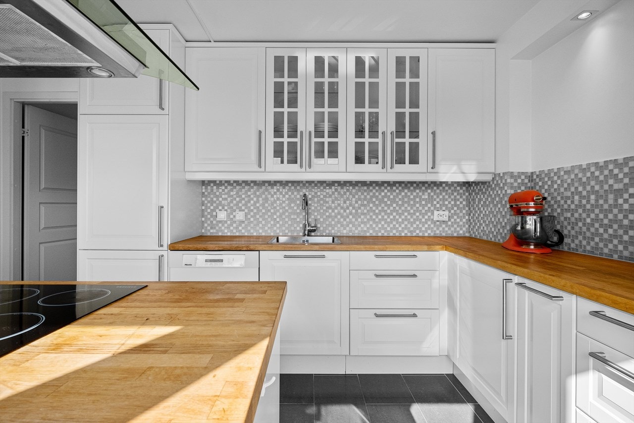 Tidløs innredning med god skap- og benkeplass, benkeplater i heltre og pent flislagt mellom benk og overskap. Galleribilde