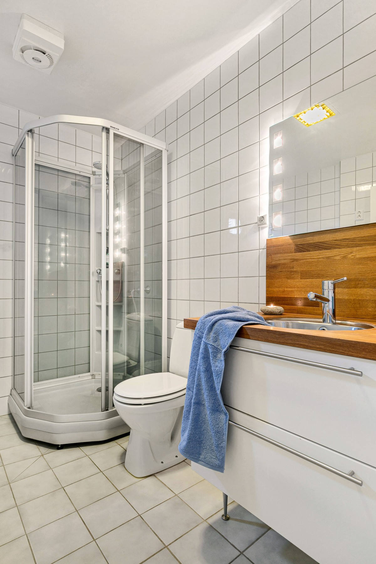 Badet er utstyrt med dusjkabinett, toalett og servant med eikeplate