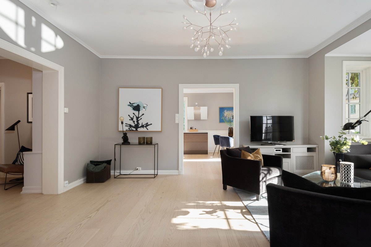 Lysvennlig stue med store åpninger til tilstøtende rom og god takhøyde Galleribilde