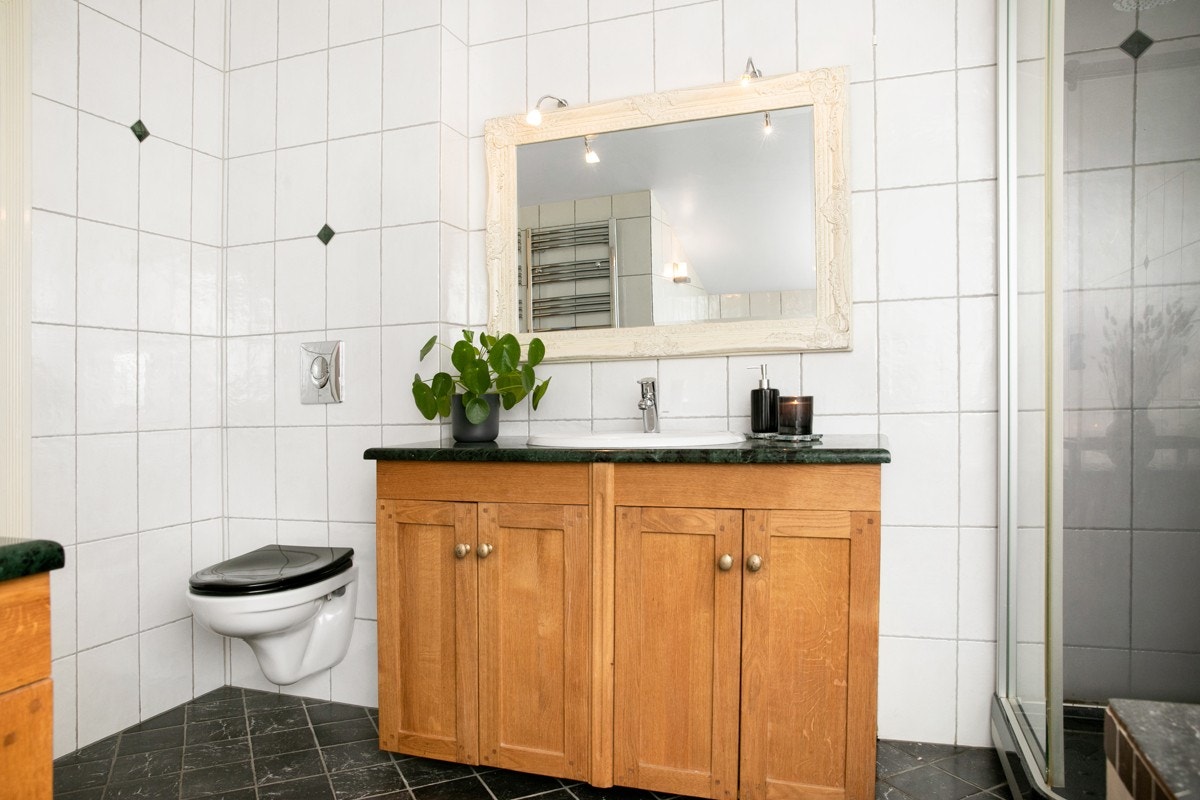 Badet er utstyrt med vegghengt toalett, innredning, dusj- Galleribilde