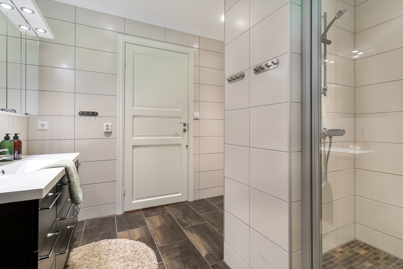 Bad har romslig dusjnisje og oppbevaringsplass i innredning Galleribilde